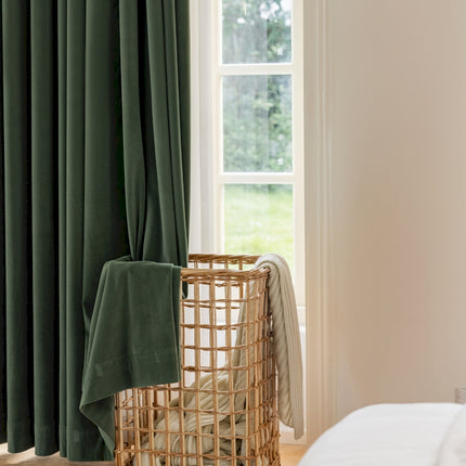 a window with a green curtain and a basket in front of it