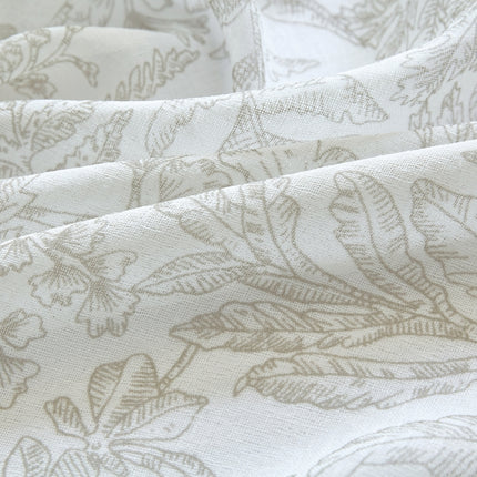 a close up of a white fabric with leaves on it