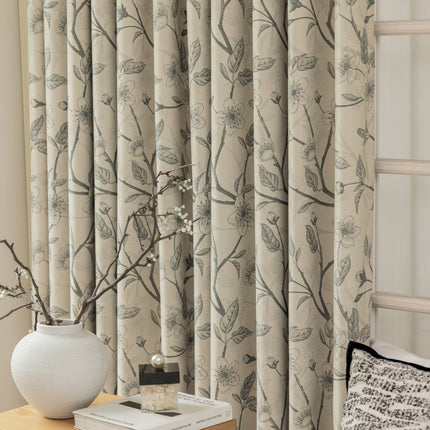 a vase with a branch on a table next to a window