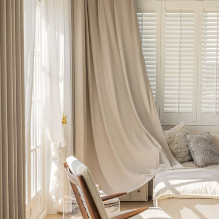 a chair sitting in front of a window covered in curtains