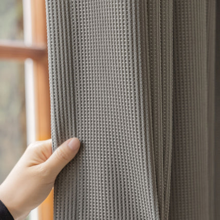 a person holding onto a curtain in front of a window