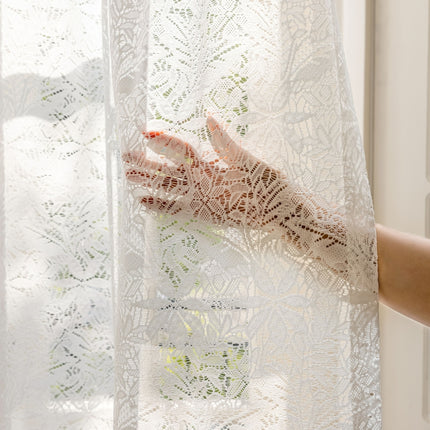 a woman's hand is seen through a lace curtain