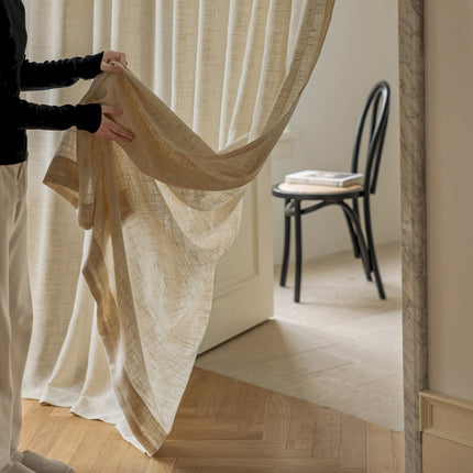 a woman holding a piece of cloth in front of a window