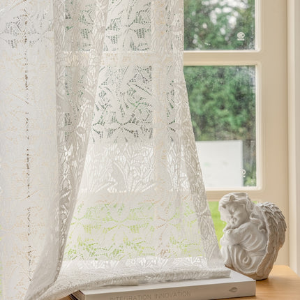 a window with a curtain and a vase on a table