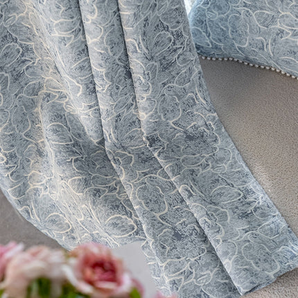 a close up of a curtain with a vase of flowers in front of it