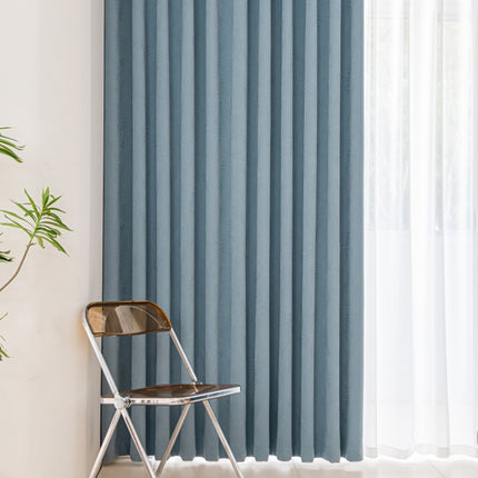 a chair sitting in front of a window with a blue curtain