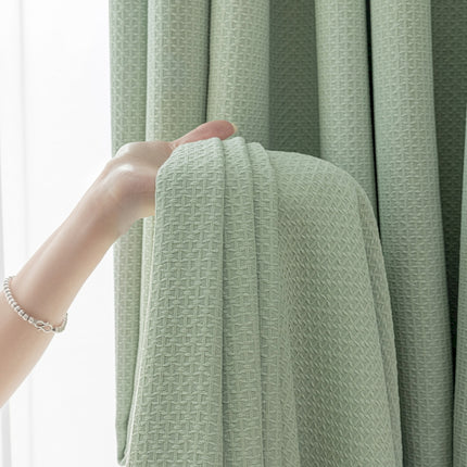 a hand reaching for a curtain in front of a window