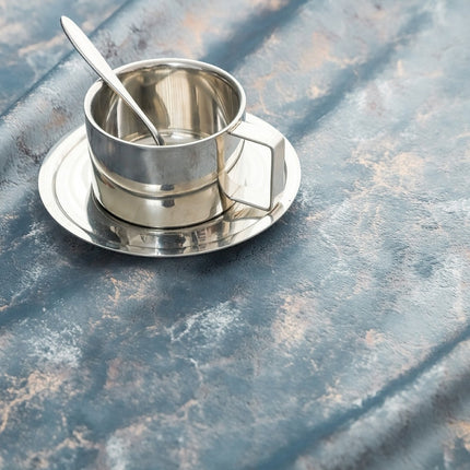 a metal cup and saucer sitting on a table