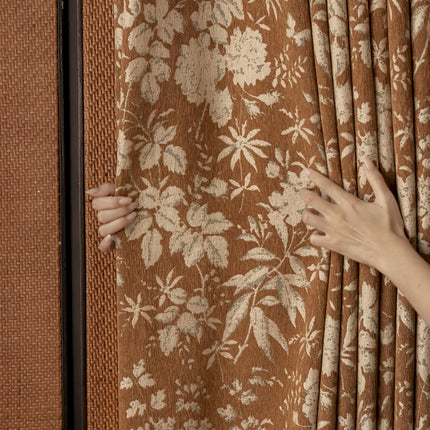 a woman's hand on a curtain with a floral pattern