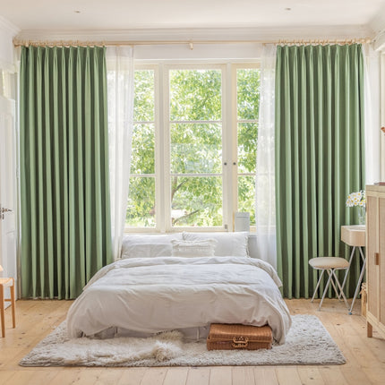 a bedroom with a large bed and green curtains