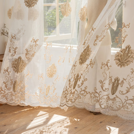a white curtain with a gold design hanging in front of a window