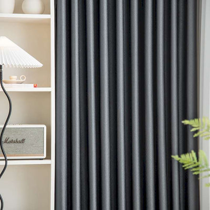 a living room with a book shelf and a black curtain