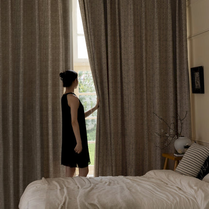 a woman standing in front of a window in a bedroom