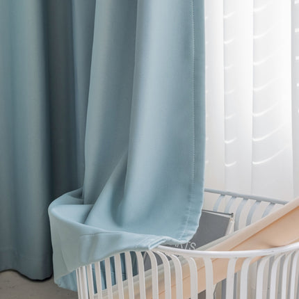 a baby crib next to a window with a blue curtain