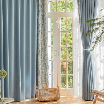 a living room with blue curtains and a basket on the floor