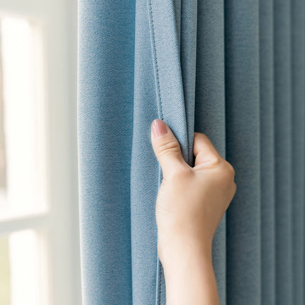 a person's hand is holding the curtain in front of a window