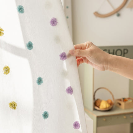 a person is holding a curtain with flowers on it
