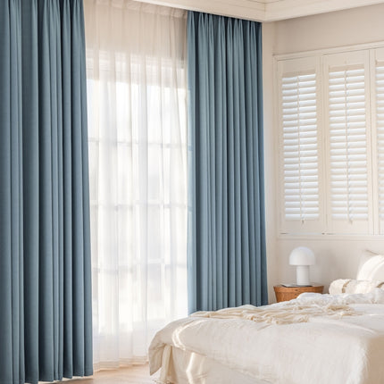 a bedroom with a white bed and blue curtains