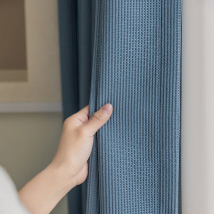 a person is opening a curtain with their hand