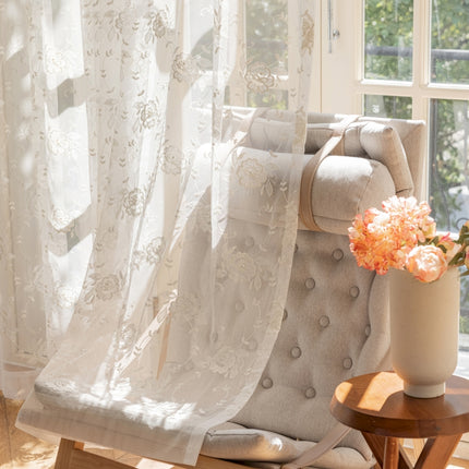 a chair with a vase of flowers on it next to a window