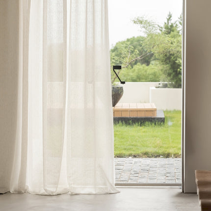 a window with a white curtain and a wooden bench