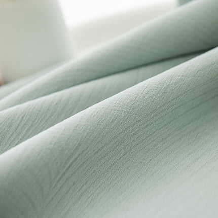 a close up of a bed with a green comforter