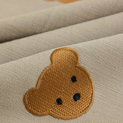 a brown teddy bear embroidered on a tan fabric