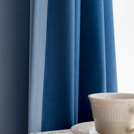 a cup and saucer on a table in front of a blue curtain