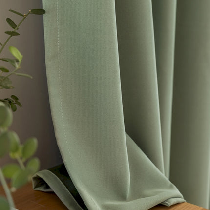 a close up of a curtain with a plant in the background
