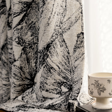a coffee cup sitting on top of a table next to a curtain