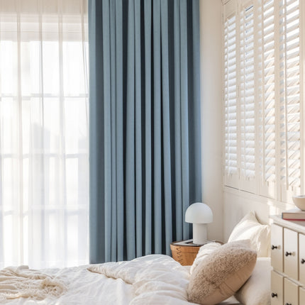 a bedroom with a white bed and blue curtains
