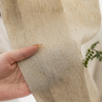 a person holding a piece of fabric with a plant in the background