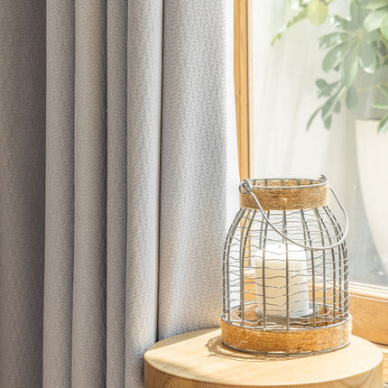 a white candle sitting on top of a table next to a window