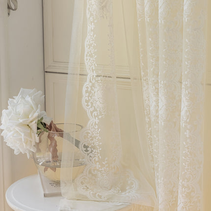 a vase with flowers on a table next to a curtain