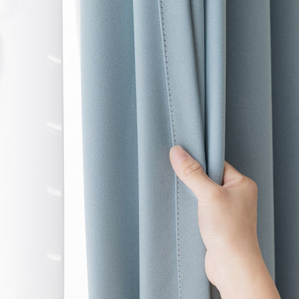 a person's hand is holding the curtain in front of a window
