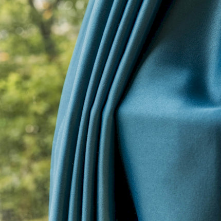 a close up of a blue curtain with trees in the background