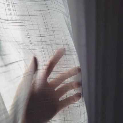 a person's hand is seen through a sheer curtain