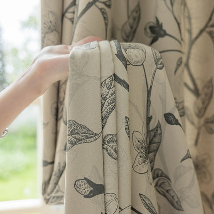 a person's hand holding a curtain with a flower pattern