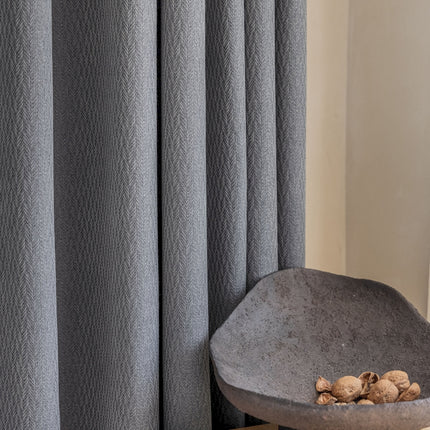 a bowl of nuts sitting on a table next to a curtain