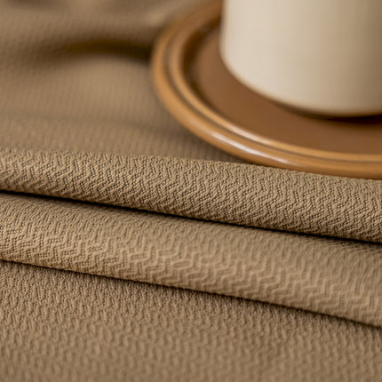 a close up of a table cloth with a cup of coffee in the background