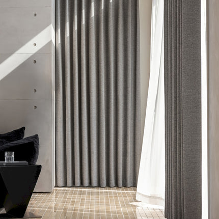 a living room with a black chair and a white curtain