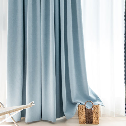 a chair sitting next to a window with a blue curtain