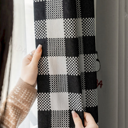 a woman holding a black and white checkered curtain