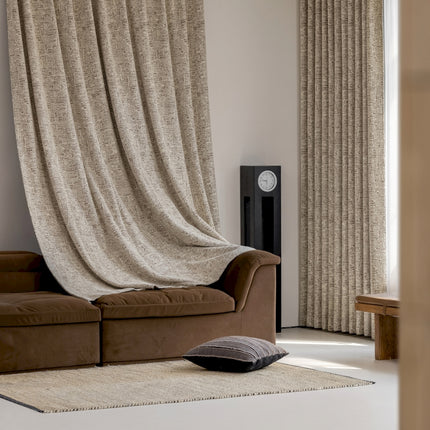 a living room with a brown couch and a tan curtain