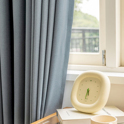 a clock sitting on top of a box next to a window