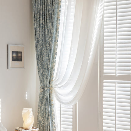 a bedroom with a window covered in white curtains