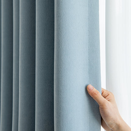 a hand is holding the curtain in front of a window