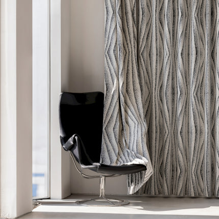 a chair sitting in front of a window next to a curtain
