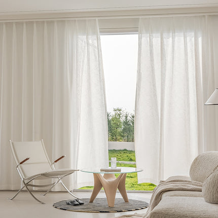 a living room with a glass table and white curtains