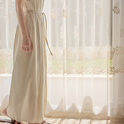 a woman in a dress standing in front of a window